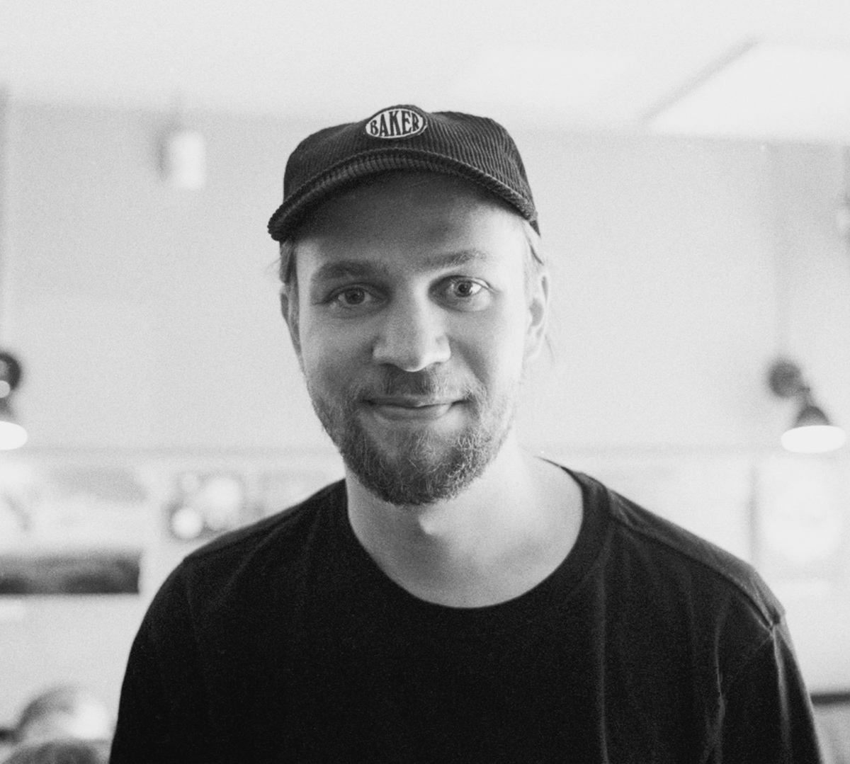 Black and white picture of a smiling designer with a cap on his head